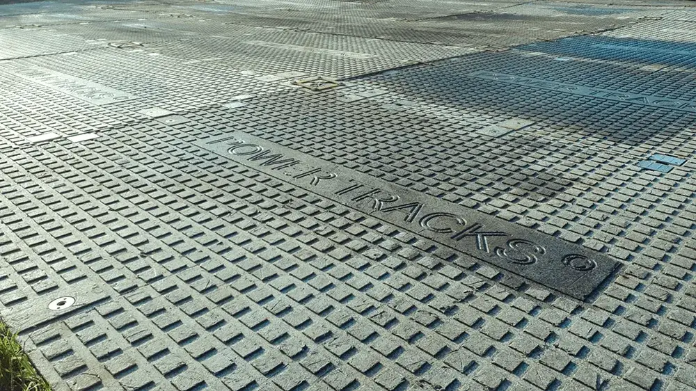 Grey interlocking PowerTrax 40 ground mats with a raised grid texture on an outdoor surface. "POWER TRACKS" is embossed on one panel.