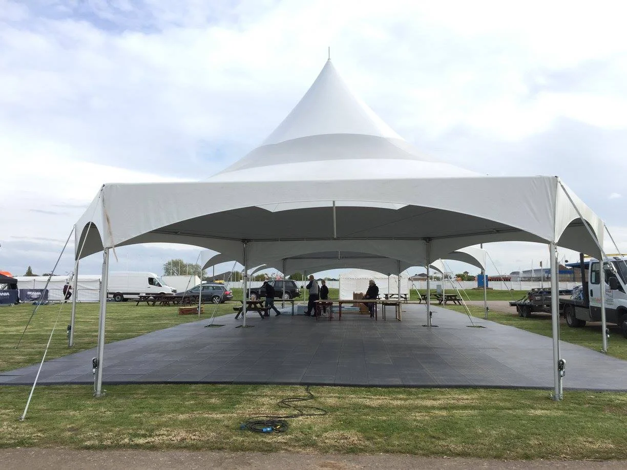 GT Trax marquee flooring panels laid under a large outdoor event tent, providing a clean, level surface for guests and furniture.