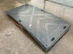 Stack of three dark grey interlocking EuroMat ground protection mats on concrete floor. Textured surface.